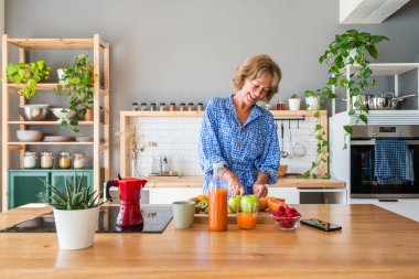 Beautiful mature senior woman at home, domestic life and leisure moments - 50-60 years old pretty female adult cooking healthy food at home in the kitchen for diet