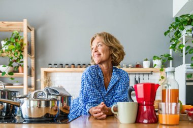 Beautiful mature senior woman at home, domestic life and leisure moments - 50-60 years old pretty female adult portrait in the kitchen at breakfast