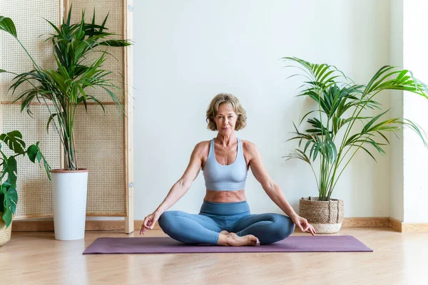 Beautiful mature senior woman at home, domestic life and leisure moments - 50-60 years old pretty female adult training in the living room