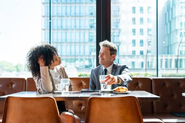Senior businessman and beautiful hispanic businesswoman meeting in a bar restaurant  - Two colleagues bonding in a cafe after work
