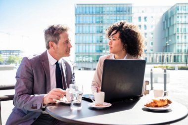 Senior businessman and beautiful hispanic businesswoman meeting in a bar restaurant  - Two colleagues bonding in a cafe after work