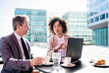 Senior businessman and beautiful hispanic businesswoman meeting in a bar restaurant  - Two colleagues bonding in a cafe after work