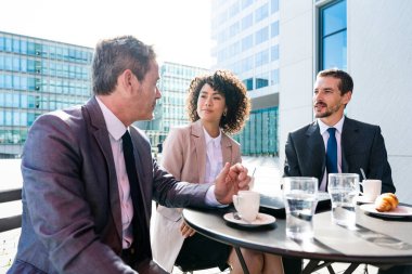Senior businessman, caucasian man and beautiful hispanic businesswoman meeting in a bar restaurant  - Three colleagues bonding in a cafe after work