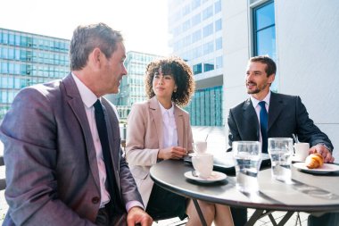Senior businessman, caucasian man and beautiful hispanic businesswoman meeting in a bar restaurant  - Three colleagues bonding in a cafe after work