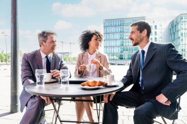 Senior businessman, caucasian man and beautiful hispanic businesswoman meeting in a bar restaurant  - Three colleagues bonding in a cafe after work