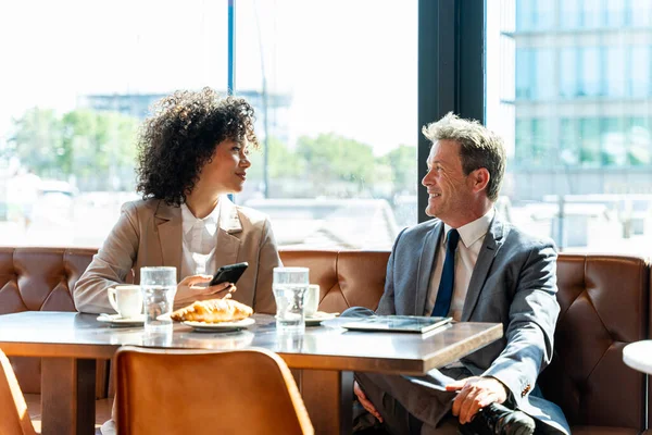 Senior businessman and beautiful hispanic businesswoman meeting in a bar restaurant  - Two colleagues bonding in a cafe after work