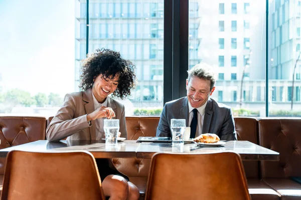 Senior businessman and beautiful hispanic businesswoman meeting in a bar restaurant  - Two colleagues bonding in a cafe after work