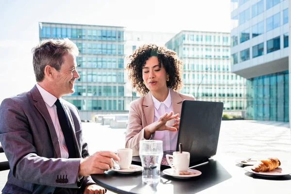 Senior businessman and beautiful hispanic businesswoman meeting in a bar restaurant  - Two colleagues bonding in a cafe after work