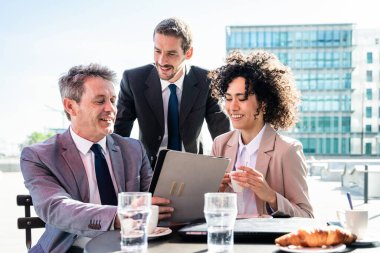 Senior businessman, caucasian man and beautiful hispanic businesswoman meeting in a bar restaurant  - Three colleagues bonding in a cafe after work