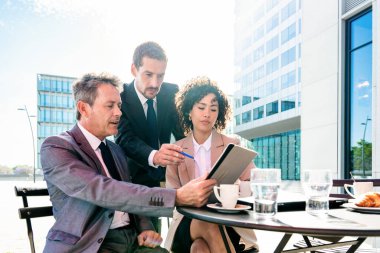 Senior businessman, caucasian man and beautiful hispanic businesswoman meeting in a bar restaurant  - Three colleagues bonding in a cafe after work