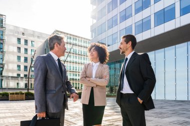 Multiracial group of business people bonding outdoors - International business corporate team wearing elegant suit meeting in a business park