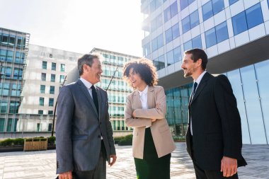 Multiracial group of business people bonding outdoors - International business corporate team wearing elegant suit meeting in a business park