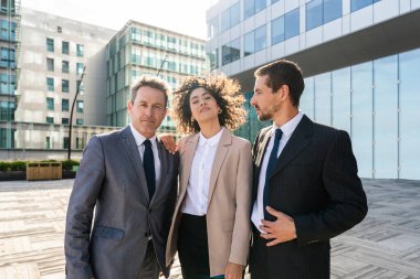 Multiracial group of business people bonding outdoors - International business corporate team wearing elegant suit meeting in a business park