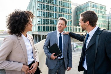 Multiracial group of business people bonding outdoors - International business corporate team wearing elegant suit meeting in a business park