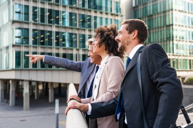 Multiracial group of business people bonding outdoors - International business corporate team wearing elegant suit meeting in a business park