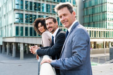 Multiracial group of business people bonding outdoors - International business corporate team wearing elegant suit meeting in a business park