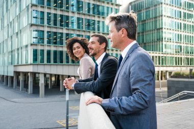 Multiracial group of business people bonding outdoors - International business corporate team wearing elegant suit meeting in a business park
