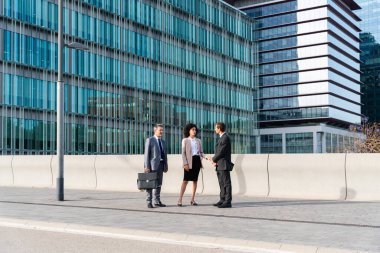 Multiracial group of business people bonding outdoors - International business corporate team wearing elegant suit meeting in a business park