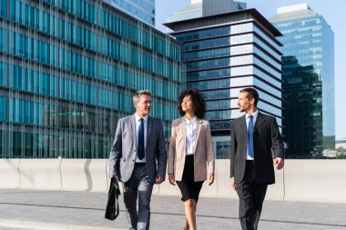 Multiracial group of business people bonding outdoors - International business corporate team wearing elegant suit meeting in a business park