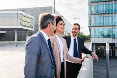 Multiracial group of business people bonding outdoors - International business corporate team wearing elegant suit meeting in a business park