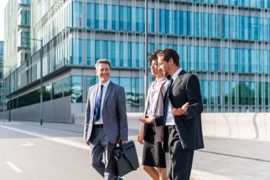 Multiracial group of business people bonding outdoors - International business corporate team wearing elegant suit meeting in a business park