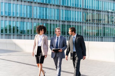 Multiracial group of business people bonding outdoors - International business corporate team wearing elegant suit meeting in a business park