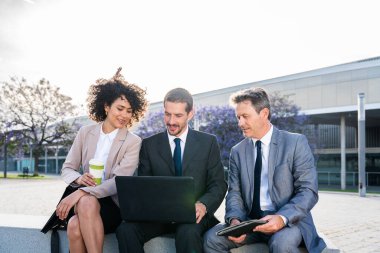 Multiracial group of business people bonding outdoors - International business corporate team wearing elegant suit meeting in a business park