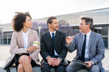 Multiracial group of business people bonding outdoors - International business corporate team wearing elegant suit meeting in a business park