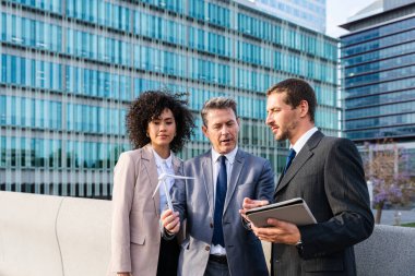 Multiracial group of business people bonding outdoors - International business corporate team wearing elegant suit meeting in a business park
