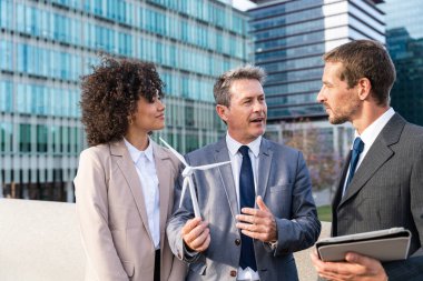 Multiracial group of business people bonding outdoors - International business corporate team wearing elegant suit meeting in a business park