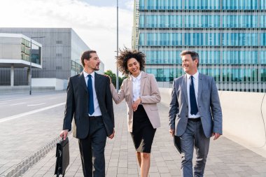 Multiracial group of business people bonding outdoors - International business corporate team wearing elegant suit meeting in a business park