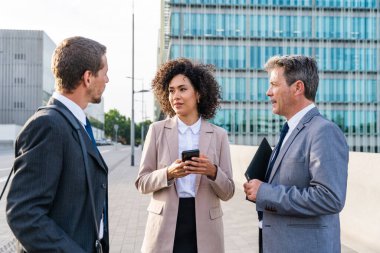 Multiracial group of business people bonding outdoors - International business corporate team wearing elegant suit meeting in a business park