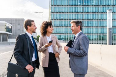 Multiracial group of business people bonding outdoors - International business corporate team wearing elegant suit meeting in a business park