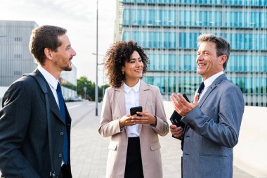 Multiracial group of business people bonding outdoors - International business corporate team wearing elegant suit meeting in a business park