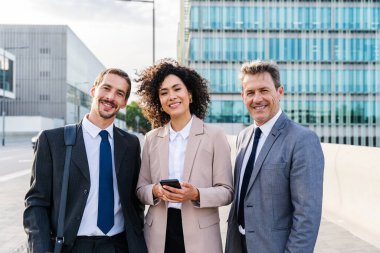 Multiracial group of business people bonding outdoors - International business corporate team wearing elegant suit meeting in a business park