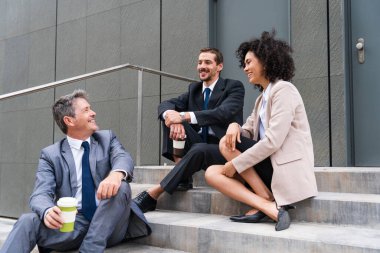 Multiracial group of business people bonding outdoors - International business corporate team wearing elegant suit meeting in a business park