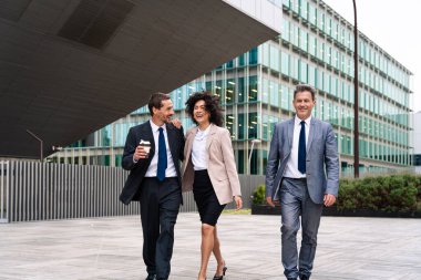 Multiracial group of business people bonding outdoors - International business corporate team wearing elegant suit meeting in a business park
