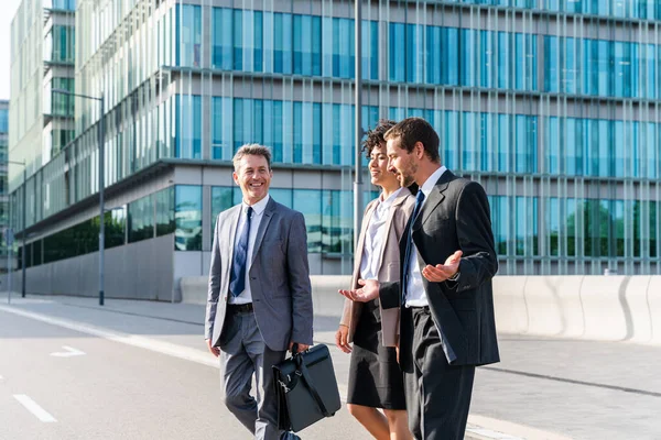 Multiracial group of business people bonding outdoors - International business corporate team wearing elegant suit meeting in a business park