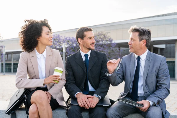 Multiracial group of business people bonding outdoors - International business corporate team wearing elegant suit meeting in a business park