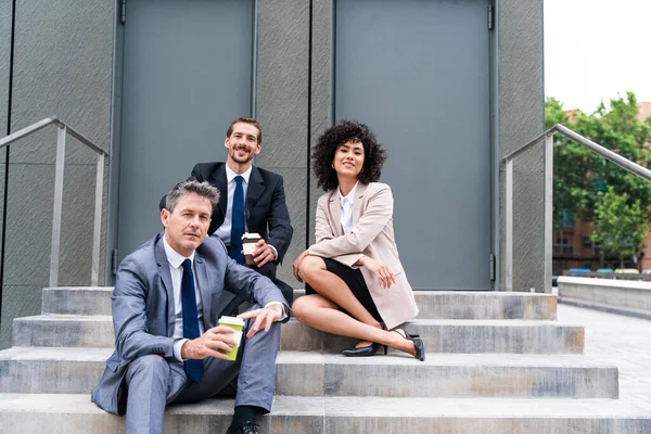 Multiracial group of business people bonding outdoors - International business corporate team wearing elegant suit meeting in a business park