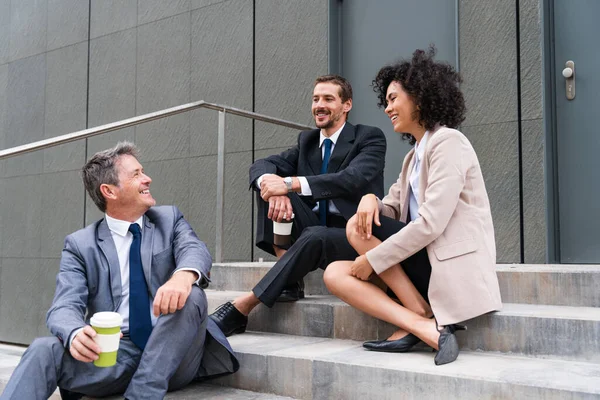 Multiracial group of business people bonding outdoors - International business corporate team wearing elegant suit meeting in a business park