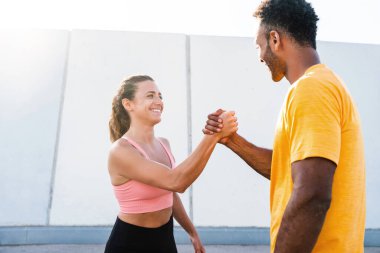 Açık havada ırklar arası spor eğitimi alan çift spor giyer ve vücut kaslarını, karın kaslarını, dayanıklılığı ve kardiyo gücünü arttırmak için dışarıda egzersiz yapar.