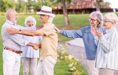 Parkta dışarıda takılan bir grup mutlu yaşlı insan - 60, 70, 80 yaşlarındaki yaşlı insanlar birlikte eğleniyor ve zaman geçiriyorlar, yaşlılar, kıdemliler ve yaşlılık hakkında kavramlar