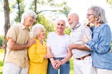 Parkta dışarıda takılan bir grup mutlu yaşlı insan - 60, 70, 80 yaşlarındaki yaşlı insanlar birlikte eğleniyor ve zaman geçiriyorlar, yaşlılar, kıdemliler ve yaşlılık hakkında kavramlar