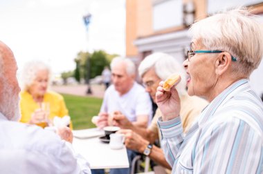 Barın dışındaki kafeteryada kaynaşan bir grup mutlu yaşlı insan - 60, 70, 80 yaşlarındaki yaşlılar birlikte eğleniyor ve zaman geçiriyorlar, yaşlılar, kıdemliler ve refah yaşlanma kavramları
