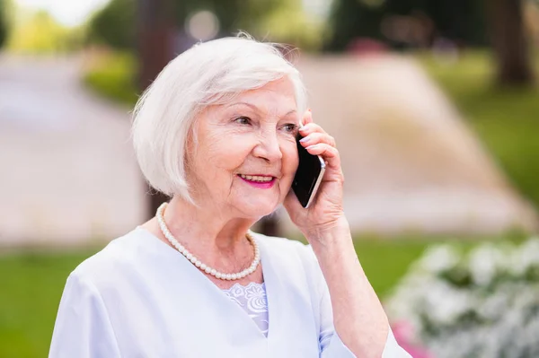 銀髪の肖像画を屋外で美しい高齢女性 現代の通信技術デバイスを使用して高齢者の女性 — ストック写真