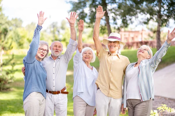 Group of happy elderly people bonding outdoors at the park - Old people in the age of 60, 70, 80 having fun and spending time together, concepts about elderly, seniority and wellness aging