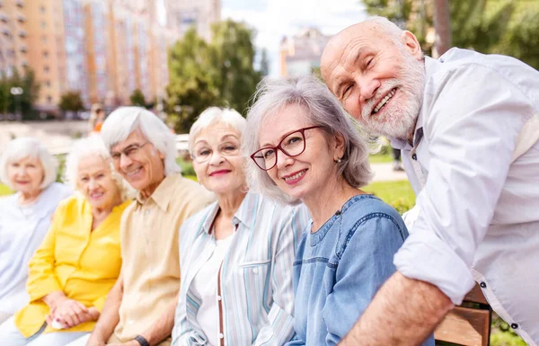 Group of happy elderly people bonding outdoors at the park - Old people in the age of 60, 70, 80 having fun and spending time together, concepts about elderly, seniority and wellness aging