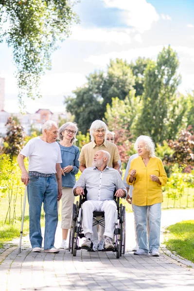 Group of happy elderly people bonding outdoors at the park - Old people in the age of 60, 70, 80 having fun and spending time together, concepts about elderly, seniority and wellness aging