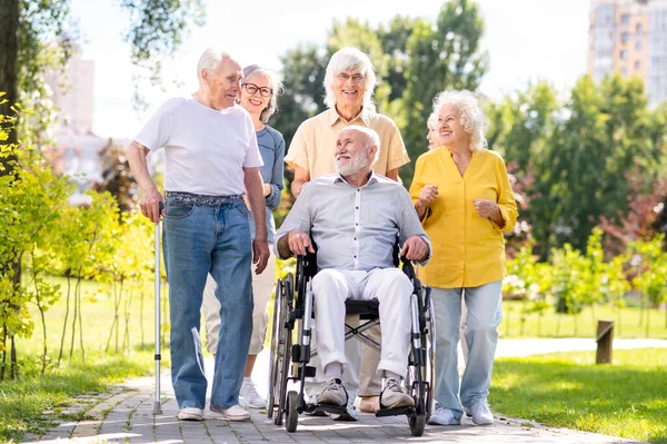 Group of happy elderly people bonding outdoors at the park - Old people in the age of 60, 70, 80 having fun and spending time together, concepts about elderly, seniority and wellness aging